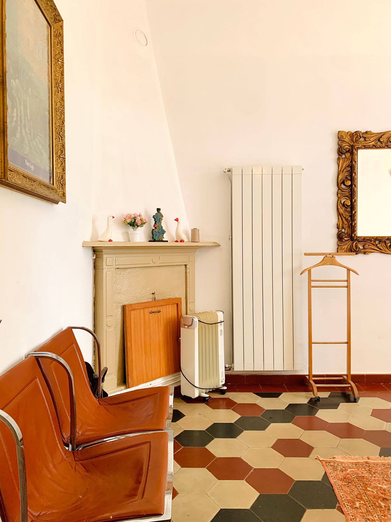 A room with a sofa, radiator, and a framed picture on the wall.