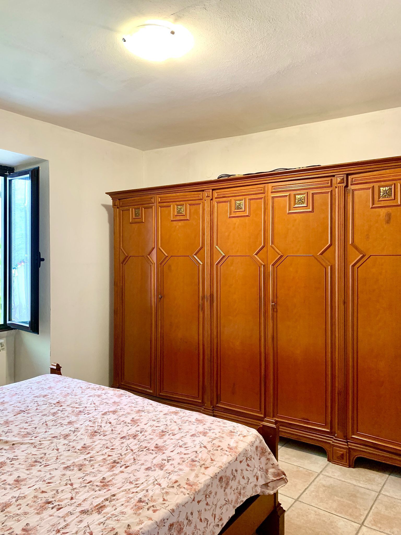 Een slaapkamer met een bed, een kast en een raam.