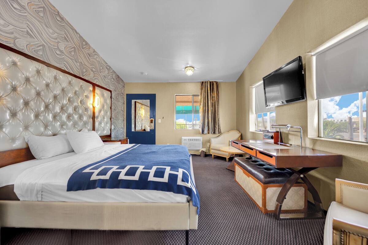 Habitación de hotel con una cama grande, un escritorio con silla, televisión y ventana con vistas.