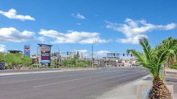 A wide street with palm trees, a Chevron sign, and a 5-star hotel in the background.