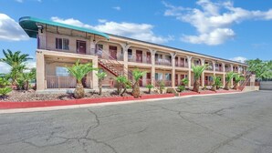 Un motel a più piani con balconi, una scala centrale e un parcheggio.