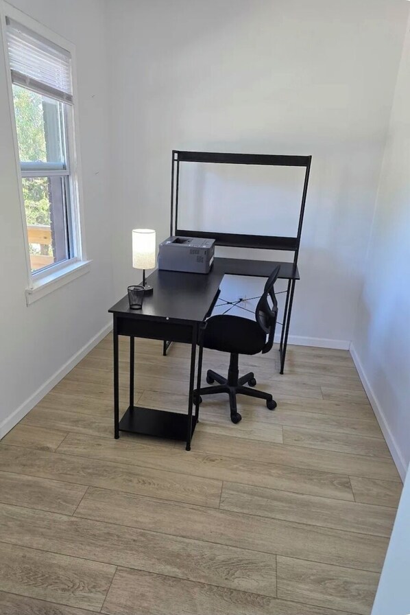 A room with a desk, chair, lamp, and window.