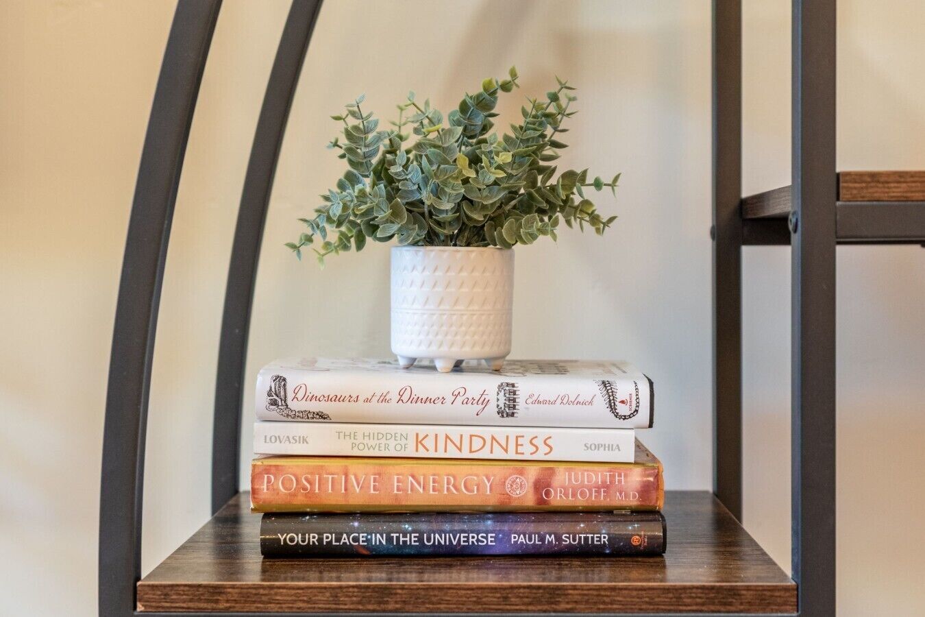 Een stapel boeken met een kleine potplant erboven, geplaatst op een houten ondergrond.