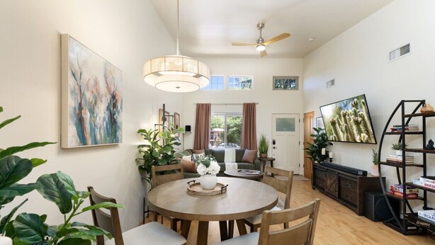 A dining area with a round table, chairs, a ceiling fan, and a television on the wall. - Uptown Sedona Red Rock Charm | Private Patio & Nice Views (Sedona)