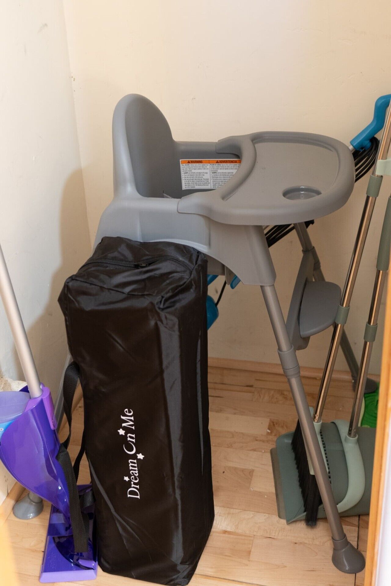 A room with a grey mobility aid, a black bag with 'Dream in Me' text, and a purple cleaning tool.