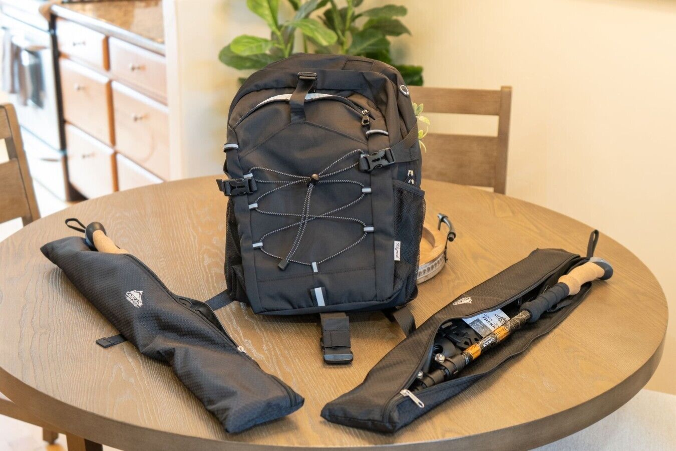 A round wooden table with a black backpack, two black pouches, and a rolled-up item.