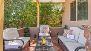 A covered patio with a sofa set, a table with a plant, and a small potted plant. - Uptown Sedona Red Rock Charm | Private Patio & Nice Views (Sedona)