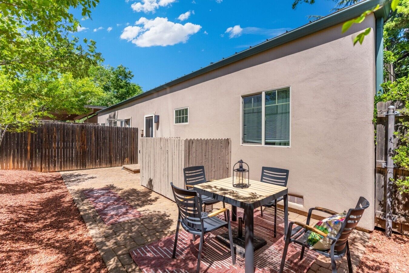 A single-story house with a patio area, a table with chairs, and a wooden fence.