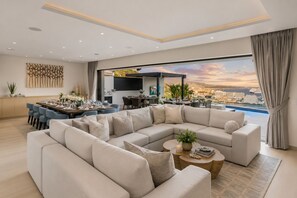 Ein modernes Wohnzimmer mit einer großen Eckcouch, einem Essbereich und Blick auf das Meer.