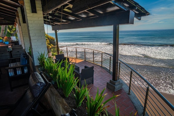 Un patio frente al mar con mobiliario exterior y vistas al océano.