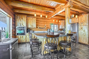 Eine Blockhausküche mit Bar, Holzwänden und hängenden Pendelleuchten.
