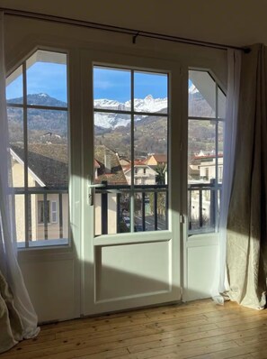 Ein Zimmer mit einem großen Fenster und Blick auf schneebedeckte Berge sowie eine Stadt darunter.