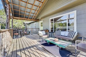 Eine überdachte Terrasse mit Gartenmöbeln, einem Holztisch und Blick auf die Umgebung.