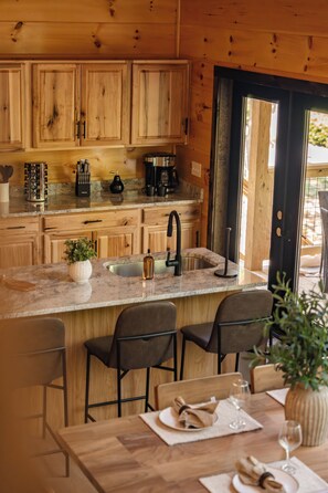 A wooden interior with a kitchen counter, sink, and bar seating. - Mountain Laurel Cabin!! Heated Pool, Theatre, Hot-tub, Games, near Pigeon Forge! (Sevierville)