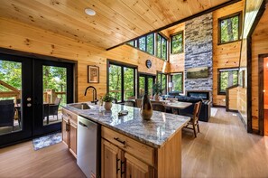 A modern kitchen with a granite countertop, wooden cabinets, and a stone fireplace. - Mountain Laurel Cabin!! Heated Pool, Theatre, Hot-tub, Games, near Pigeon Forge! (Sevierville)