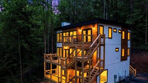 Eine mehrstöckige Holzhütte mit einer Terrasse, umgeben von Bäumen.