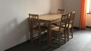 A dining area with a wooden table and chairs, a tiled floor, and a window with curtains. - Chasa Strimer, (Zernez) by Interhome (Zernez)