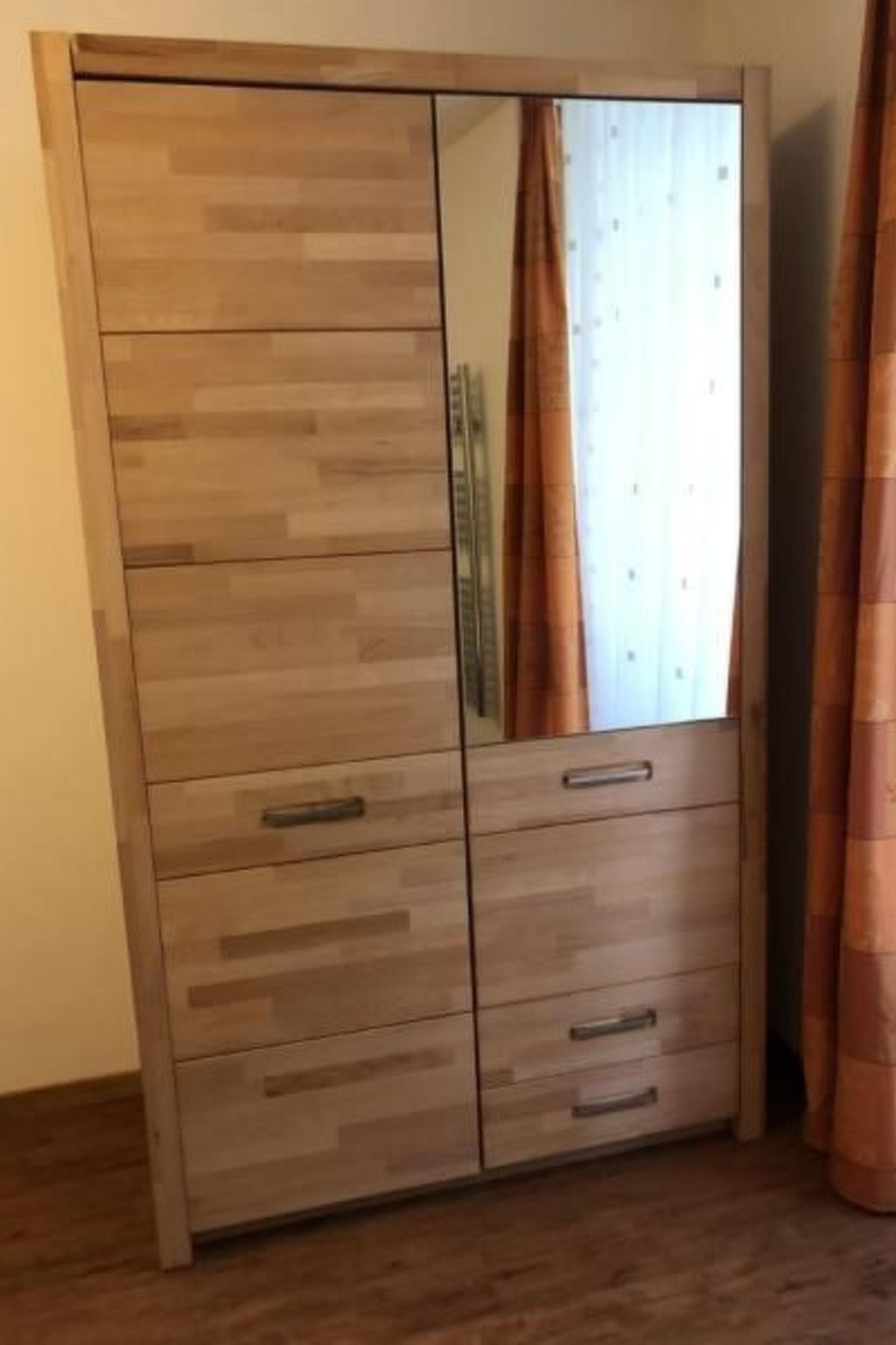 A wardrobe with multiple drawers and a mirror.