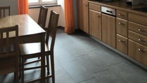 A kitchen with wooden cabinets, a dining table with chairs, and a window with curtains. - Chasa Strimer, (Zernez) by Interhome (Zernez)