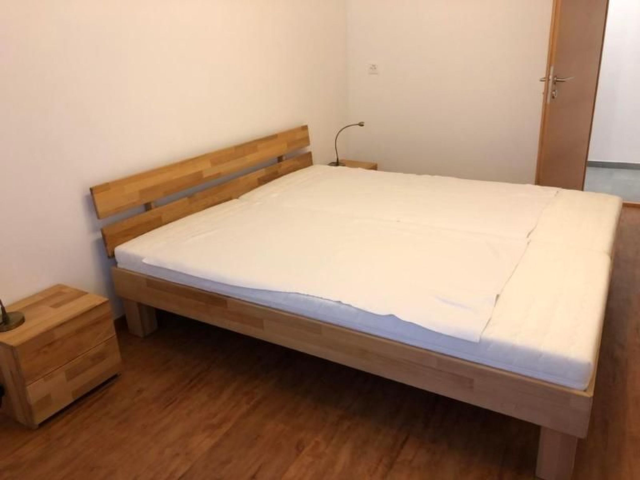 A single bed with a wooden headboard and footboard, a bedside table, and a wooden nightstand.