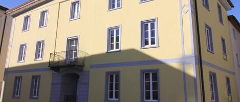 Edifício amarelo com várias janelas e base de pedra.