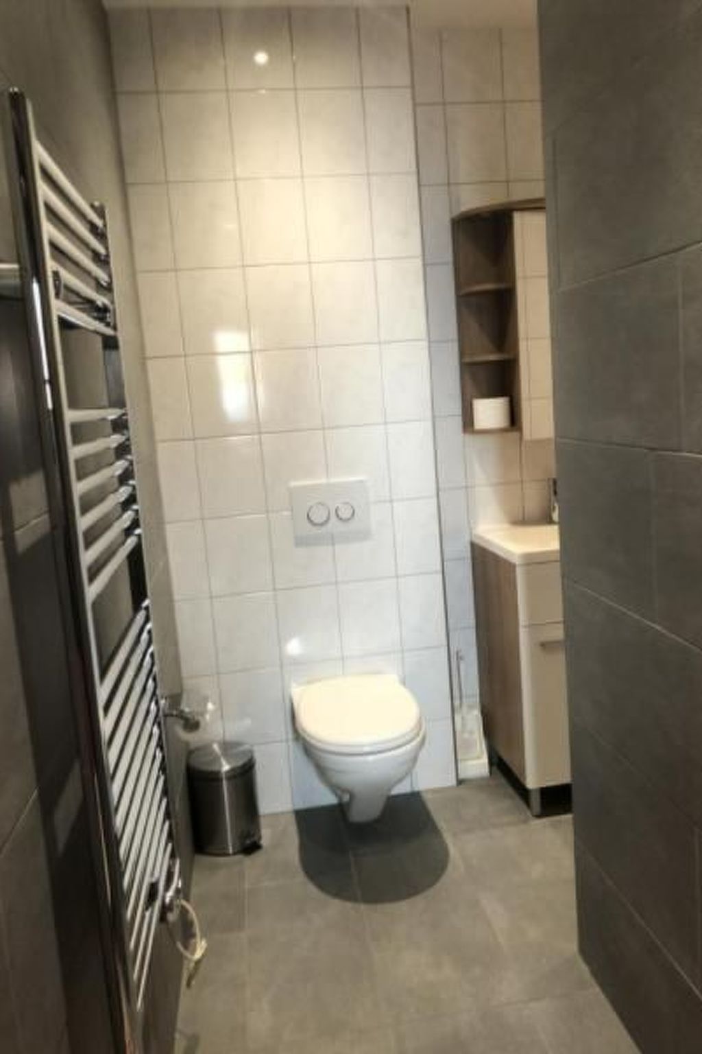 Kylpyhuone, jossa on wc, roskakori, pyyhekoukku ja kaappi.