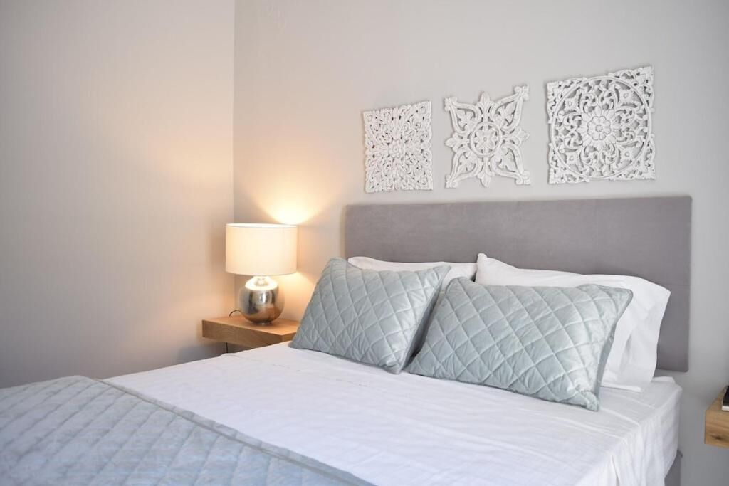 A bed with a quilted pillow, a bedside lamp, and decorative wall art.