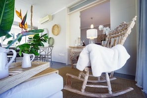 A room with a rocking chair, a coffee table with pitchers, a plant, and a mirror. - Koupeli 3 Bedroom Apartment (Chania)