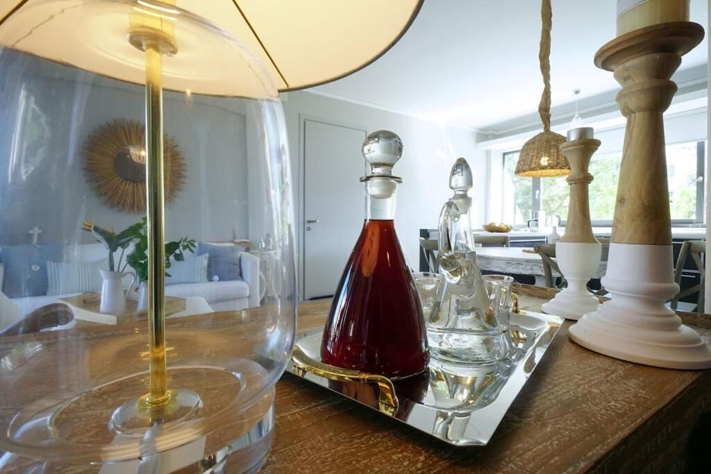 A dining area with a table set for two, a lamp, and a decorative glass pitcher.