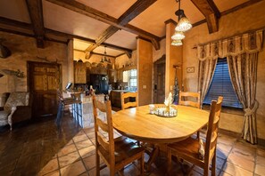 A rustic dining area with a wooden table and chairs, a chandelier, and a stone fireplace. - A Whimsical Castle in Murphy NC (Murphy)