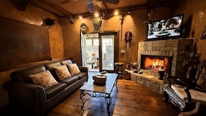 Ein gemütliches Wohnzimmer mit Kamin, Ledersofa und Fernseher.