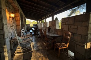 A covered outdoor dining area with stone walls, wooden furniture, and a grill. - A Whimsical Castle in Murphy NC (Murphy)