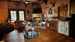 Ein rustikales Interieur mit Kamin aus Stein, Holzmöbeln und Hirschgeweihen an der Wand.