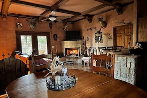 A rustic interior with a stone fireplace, wooden furniture, and deer antlers on the wall.