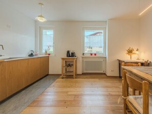 A modern kitchen with wooden cabinetry, a built-in sink, and a small wooden table with a kettle and cups. - La Casa di Bruna by Interhome (Spiazzo)