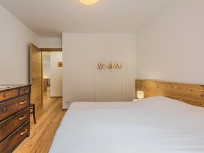 A bedroom with a wooden dresser, a bed, and a wooden headboard.