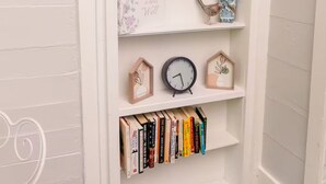 A white bookshelf with decorative items, a clock, and books.