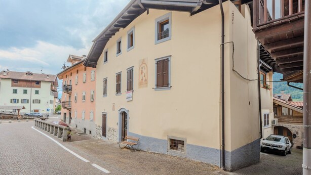 Une rue bordée d’immeubles, avec un banc et une voiture garée.