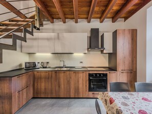 A modern kitchen with wooden cabinets, a built-in oven, and a microwave. - Apartment Silvia by Interhome (Caderzone Terme)