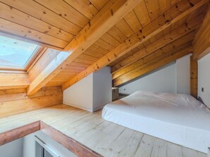 A bedroom with a sloped wooden ceiling, a skylight, and a bed. - Apartment Silvia by Interhome (Caderzone Terme)