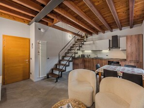 A modern kitchen with wooden cabinets, a built-in microwave, and a dining area with a table and chairs. - Apartment Silvia by Interhome (Caderzone Terme)
