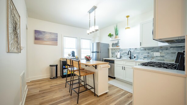 A modern kitchen with a central island, white cabinetry, and a stone backsplash. - 2-bedroom apartment in wonderful Indianapolis near State Fairgrounds (Indianapolis)