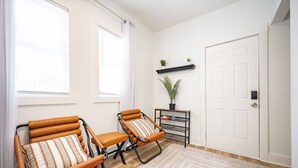 A room with two lounge chairs, a small table with a potted plant, a white door, and a window with curtains. - 2-bedroom apartment in wonderful Indianapolis near State Fairgrounds (Indianapolis)