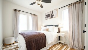 A bedroom with a bed, bedside table, lamp, curtains, and a ceiling fan. - 2-bedroom apartment in wonderful Indianapolis near State Fairgrounds (Indianapolis)
