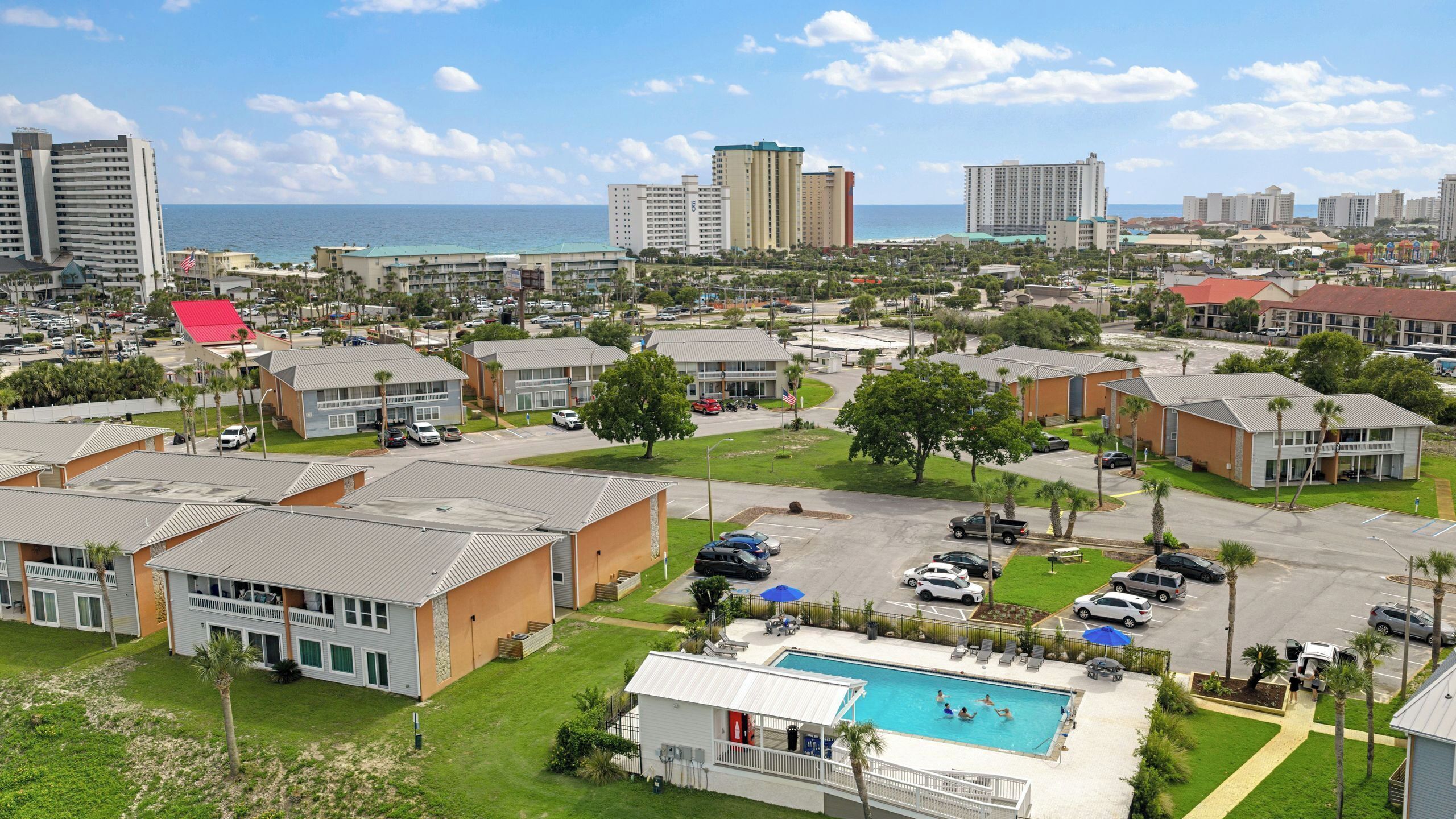 A residential area with a swimming pool, multiple-story buildings, and a view of the ocean.