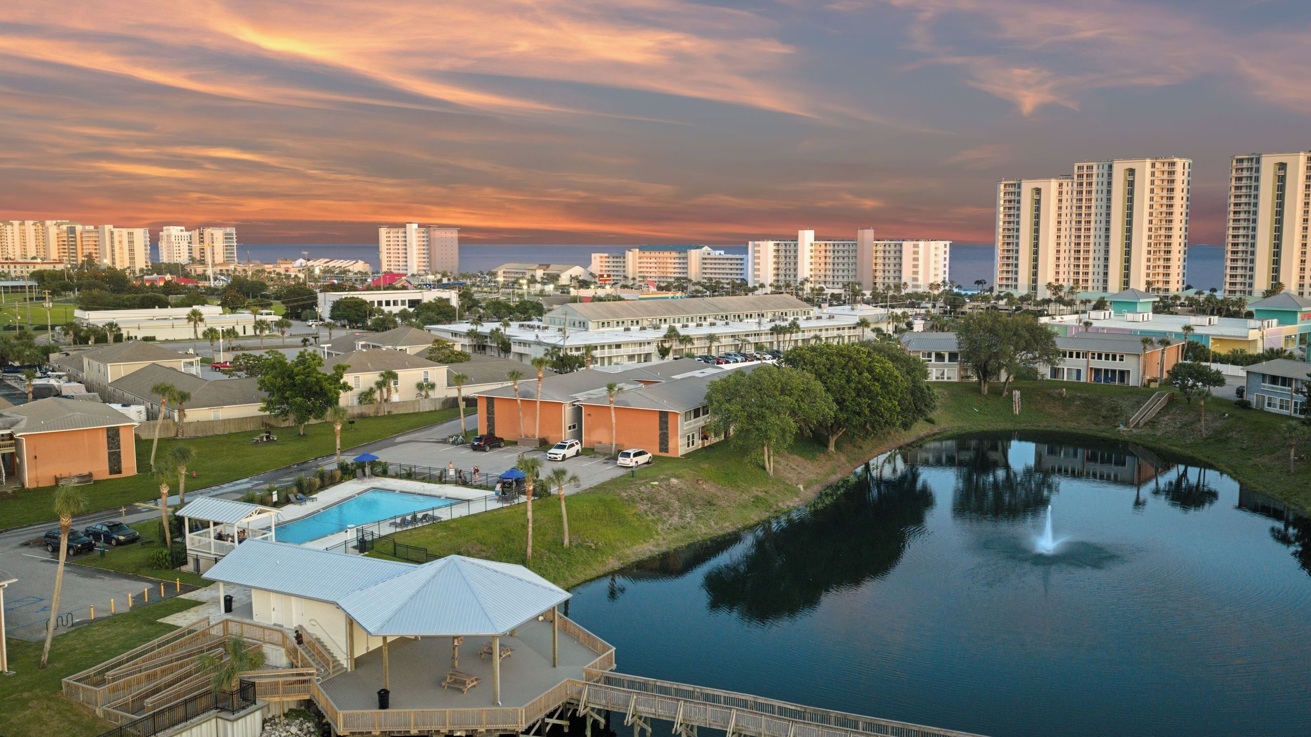 A resort area with a swimming pool, a dock, and a view of the city skyline.