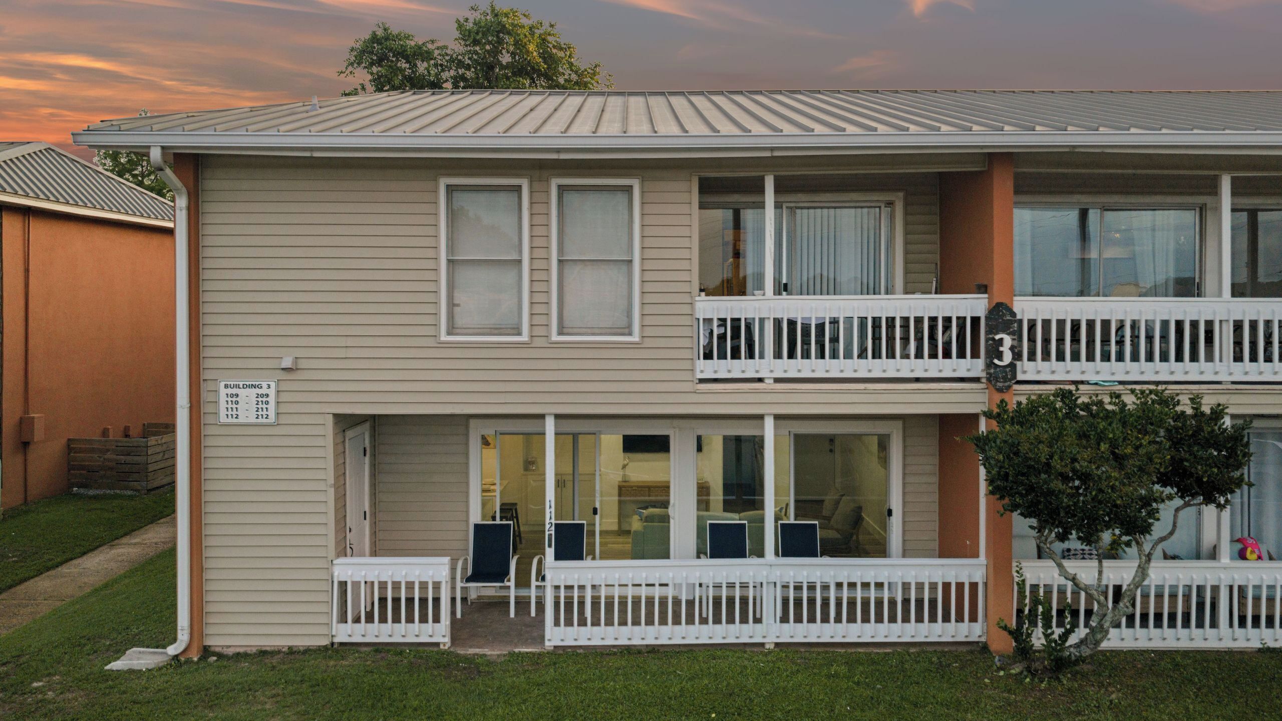 A two-story building with a balcony on the second floor, a covered entrance, and a small porch area.