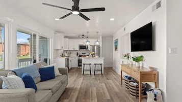 A modern kitchen with white cabinets, a central island, and a ceiling fan.