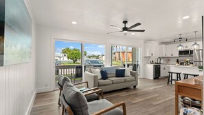 A spacious living area with a sofa, a dining table, and a kitchen with white cabinets and modern appliances. - Gulf Terrace Getaway by Avantstay Shared Pool + Tennis Near Henderson Beach + Destin Commons (Destin)