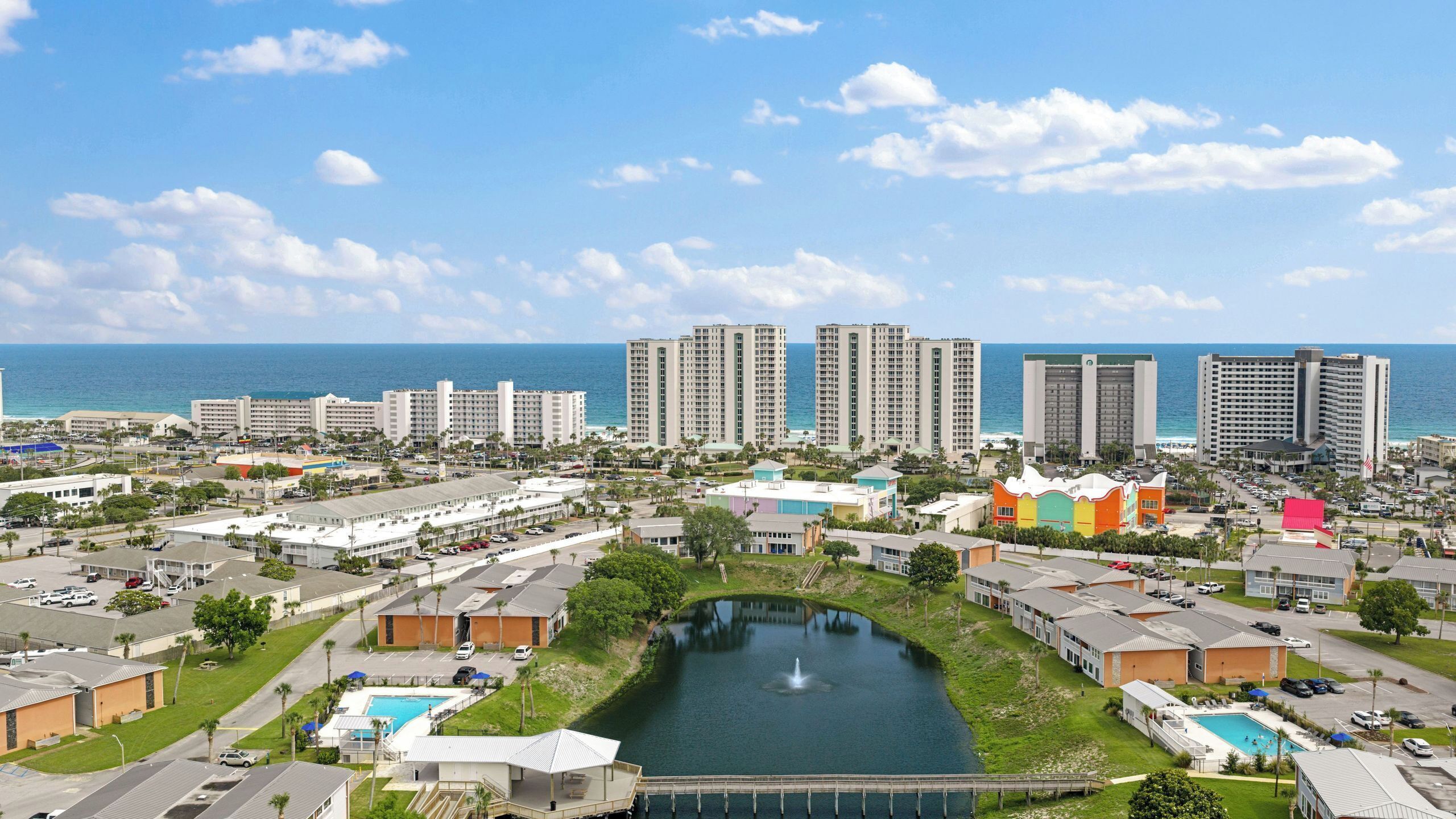 A coastal resort area with high-rise hotels, a central swimming pool, and a marina.